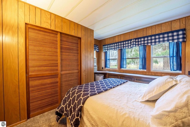 carpeted bedroom with a closet, multiple windows, and wooden walls