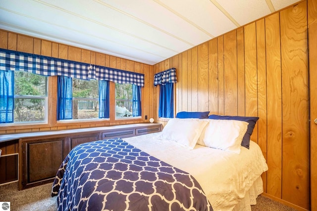 carpeted bedroom featuring multiple windows and wooden walls