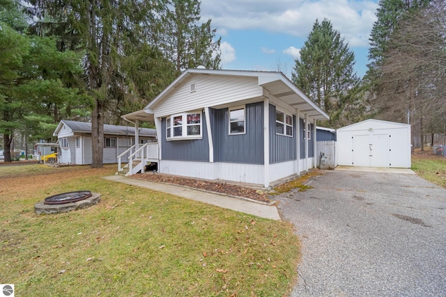 view of front of house featuring an outdoor fire pit, a front lawn, and a storage shed