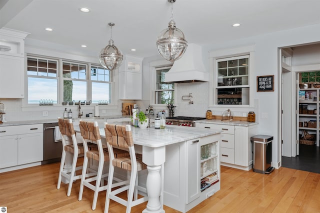 kitchen with white cabinetry, tasteful backsplash, light hardwood / wood-style flooring, a kitchen island, and custom exhaust hood