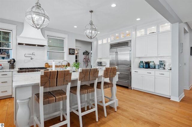 kitchen with backsplash, white cabinets, light wood-type flooring, and stainless steel appliances