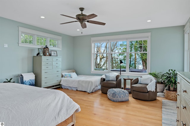 bedroom with ceiling fan, light wood-type flooring, and multiple windows