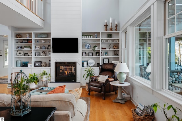 living room featuring a fireplace, a towering ceiling, and hardwood / wood-style flooring