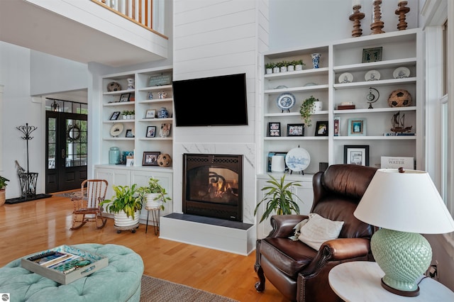 living room featuring hardwood / wood-style floors, a high end fireplace, and a high ceiling