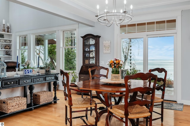 dining room with an inviting chandelier, light hardwood / wood-style flooring, and crown molding