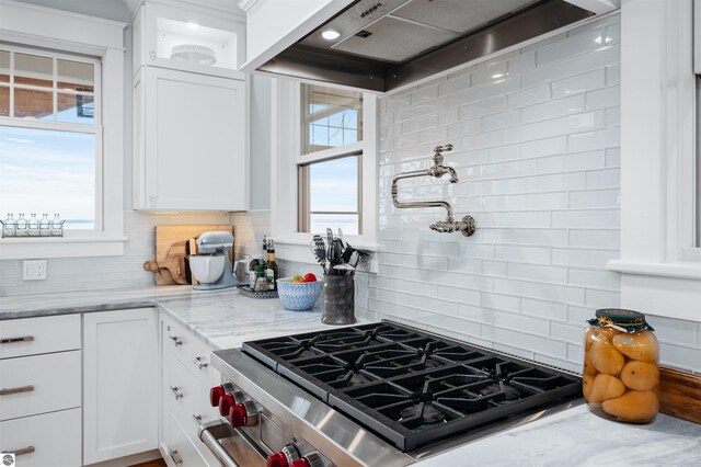 91 S Nanagosa Trl, Suttons Bay, MI 49682 - kitchen with high end stainless steel range oven, wall chimney exhaust hood, tasteful backsplash, and white cabinets