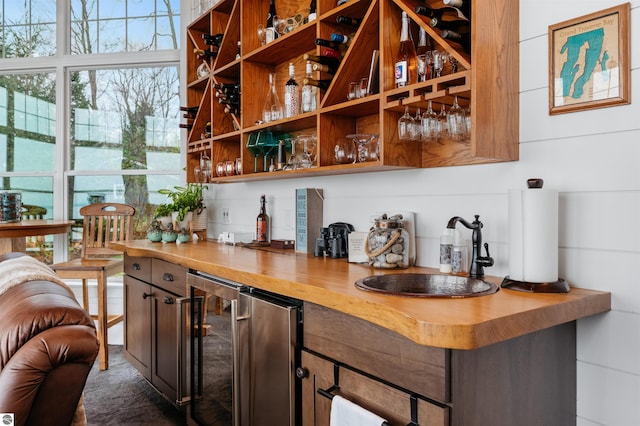 bar featuring butcher block countertops, sink, and wine cooler