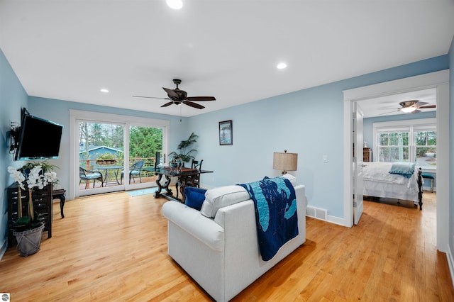 living room with plenty of natural light, ceiling fan, and light wood-type flooring