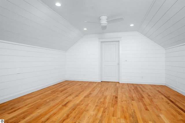 additional living space featuring light hardwood / wood-style floors, vaulted ceiling, ceiling fan, and wood walls