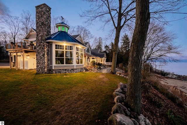 back house at dusk with a yard and a wooden deck