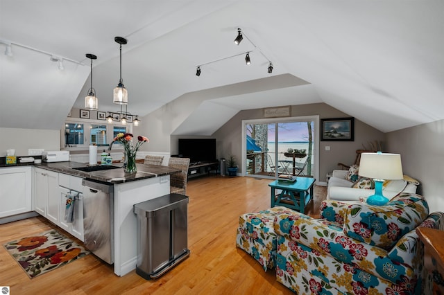 kitchen featuring lofted ceiling, white cabinets, sink, stainless steel dishwasher, and light wood-type flooring