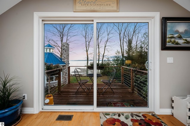 doorway with wood-type flooring and vaulted ceiling