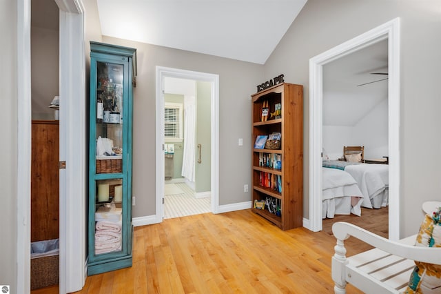 hallway with hardwood / wood-style floors and vaulted ceiling