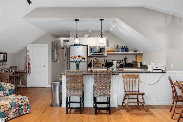 91 S Nanagosa Trl, Suttons Bay, MI 49682 - kitchen with appliances with stainless steel finishes, dark countertops, a breakfast bar area, vaulted ceiling, and track lighting