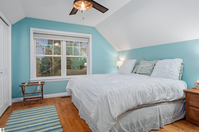 bedroom with light wood-type flooring, a closet, ceiling fan, and lofted ceiling