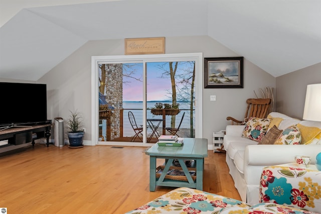 living room featuring hardwood / wood-style floors, a water view, and lofted ceiling