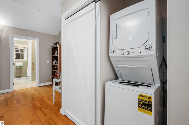 laundry area featuring stacked washing maching and dryer and light hardwood / wood-style flooring