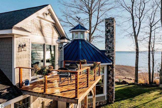 deck with a water view and a lawn