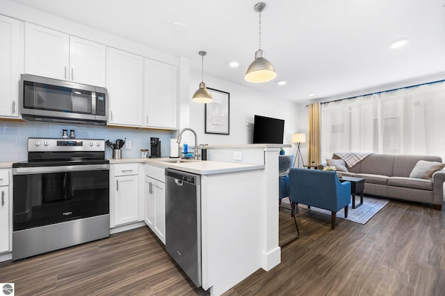 kitchen featuring kitchen peninsula, stainless steel appliances, sink, pendant lighting, and white cabinets