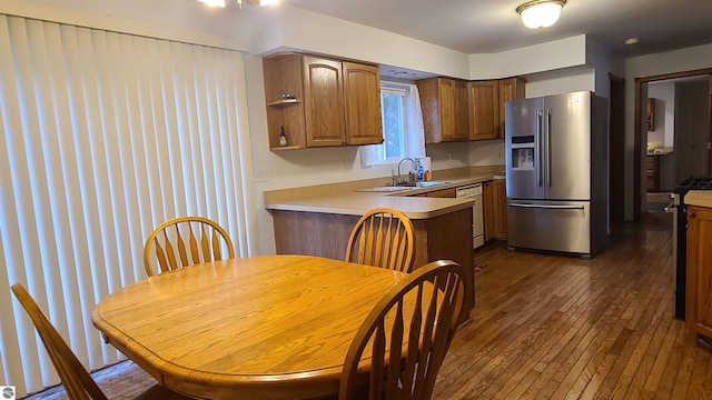 kitchen with sink, kitchen peninsula, stainless steel appliances, and dark wood-type flooring