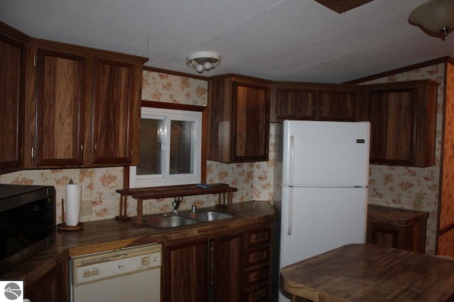 kitchen with dark brown cabinets, white appliances, lofted ceiling, and sink