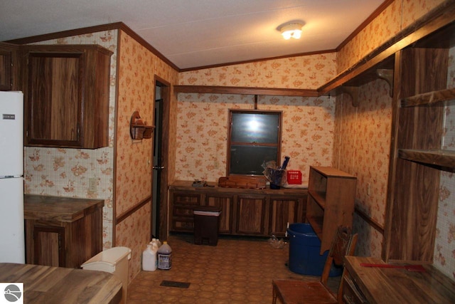 interior space with dark brown cabinets, white fridge, vaulted ceiling, and ornamental molding