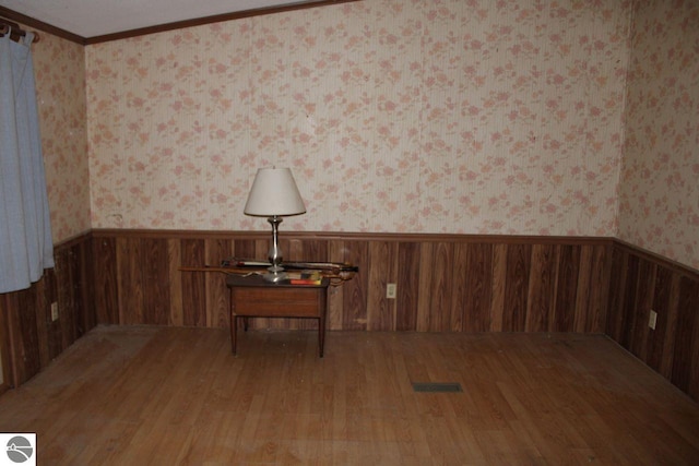 unfurnished room featuring crown molding, hardwood / wood-style floors, and wooden walls