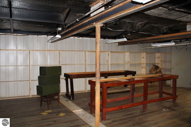 basement featuring wood walls and dark wood-type flooring