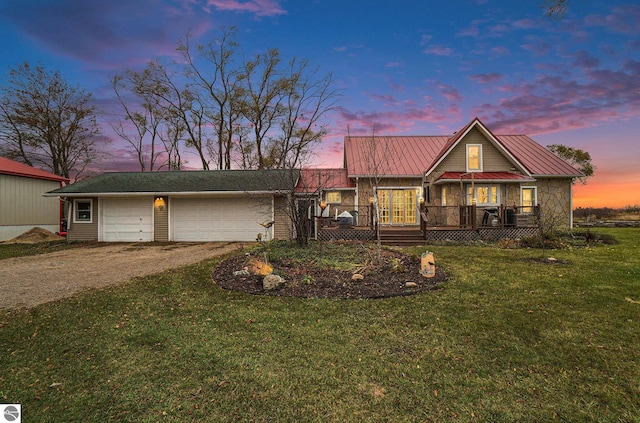 view of front of property with covered porch, a garage, and a lawn