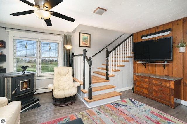 interior space featuring wood walls, ceiling fan, a baseboard heating unit, and hardwood / wood-style flooring