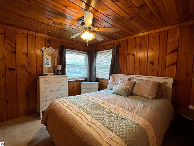 carpeted bedroom with ceiling fan, wood ceiling, and wood walls