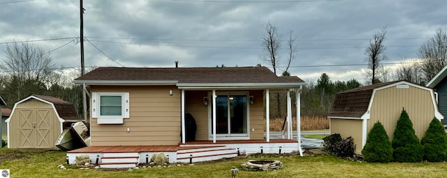 rear view of property with a lawn, a porch, a shed, and an outdoor fire pit