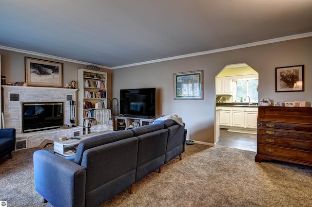 carpeted living room featuring sink, crown molding, and a brick fireplace