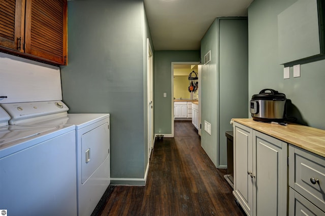 clothes washing area featuring cabinets, dark wood-type flooring, and washing machine and clothes dryer