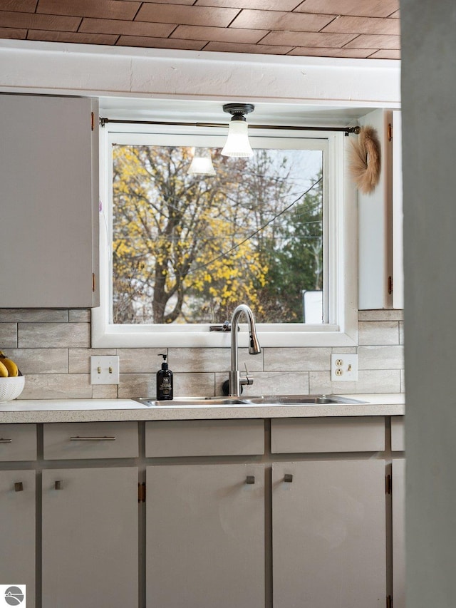 kitchen featuring decorative backsplash, a healthy amount of sunlight, white cabinetry, and sink