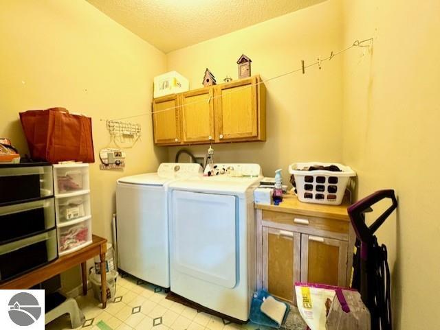 washroom with separate washer and dryer, cabinets, and a textured ceiling