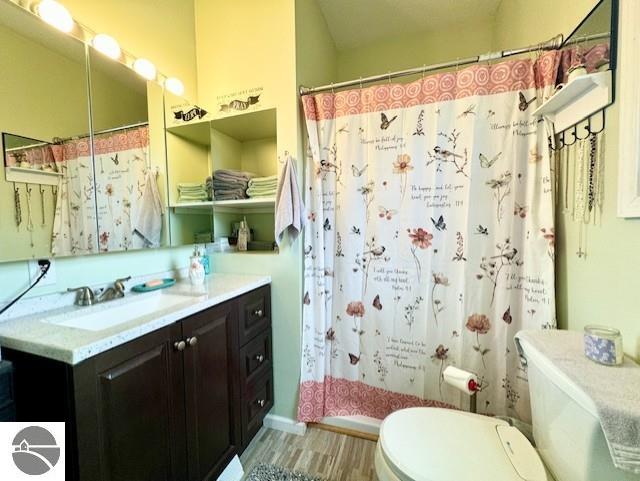 full bathroom featuring shower / bath combo with shower curtain, hardwood / wood-style floors, vanity, and toilet