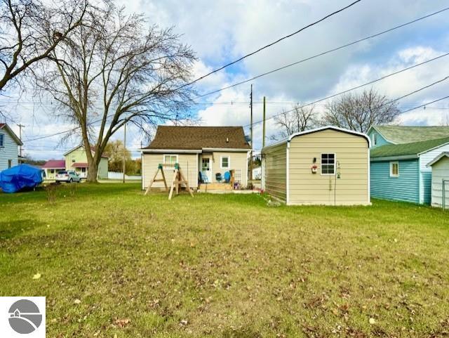 back of house with a storage unit and a yard