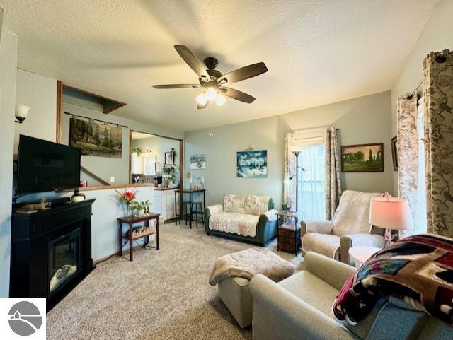 carpeted living room featuring a textured ceiling and ceiling fan