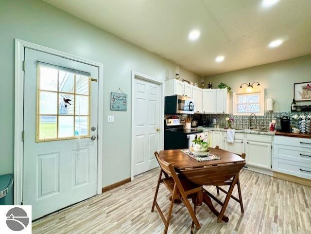 kitchen with white cabinets, stainless steel appliances, light hardwood / wood-style flooring, and tasteful backsplash