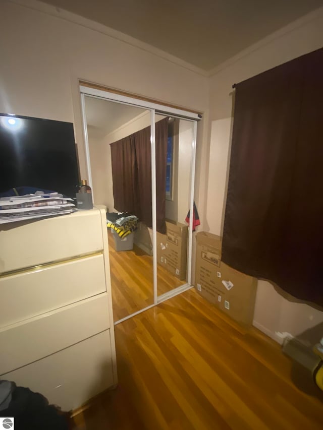 unfurnished bedroom with hardwood / wood-style flooring, a closet, and crown molding