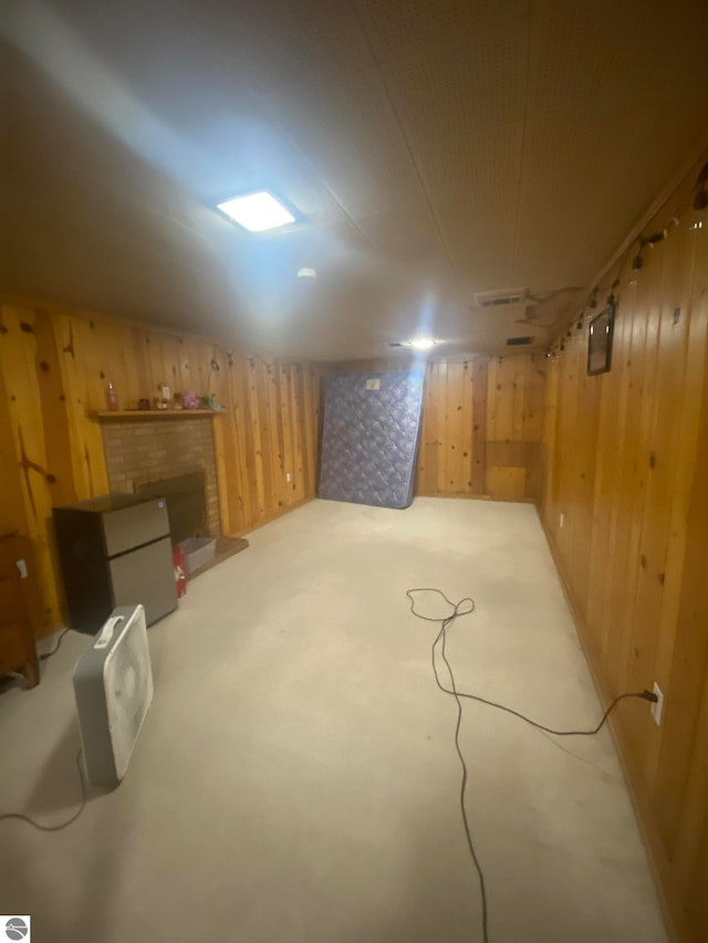 basement featuring a brick fireplace and wood walls