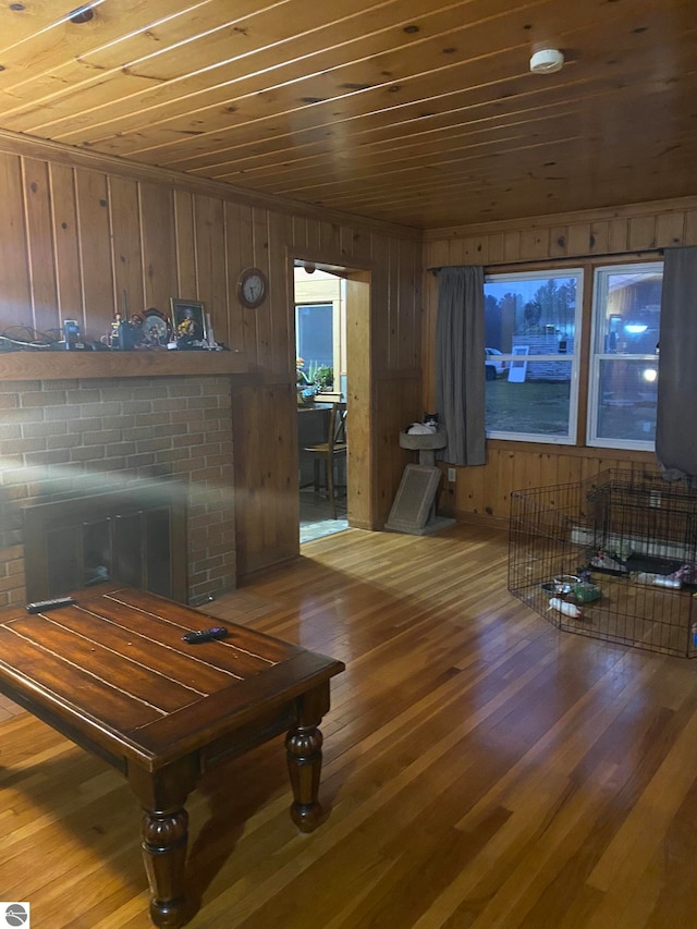 living room with wooden ceiling, a fireplace, wood-type flooring, and wood walls