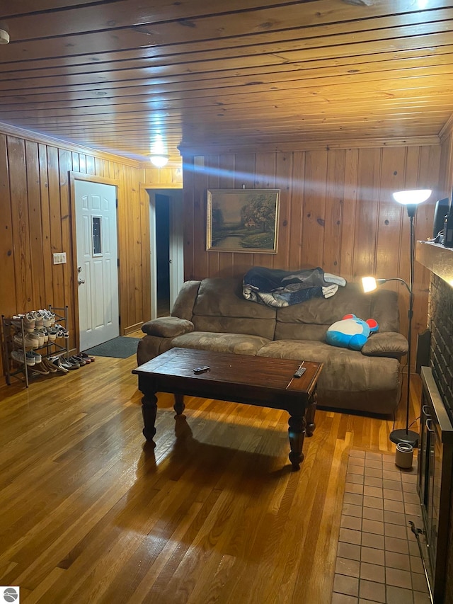 living room with light hardwood / wood-style floors, a brick fireplace, wooden walls, and wood ceiling