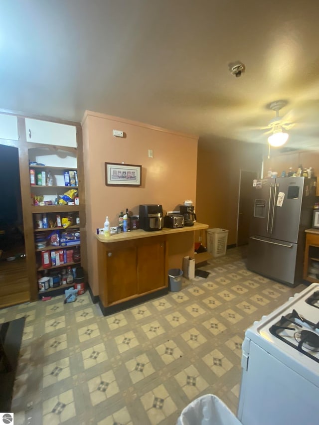 kitchen featuring white range with gas cooktop, stainless steel fridge, and ceiling fan