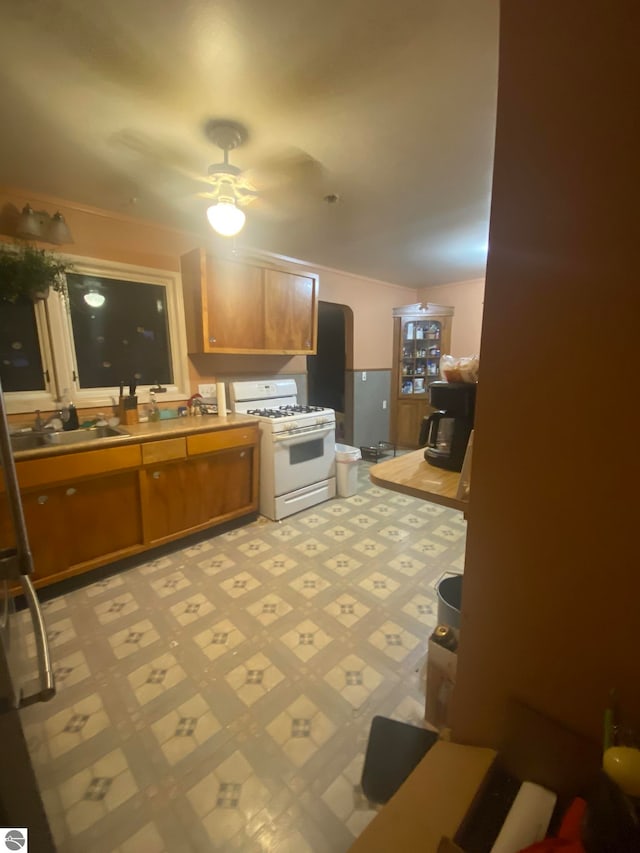 kitchen with white range with gas cooktop, ceiling fan, and sink