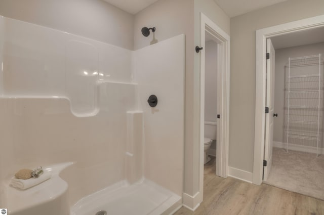 bathroom with a shower, toilet, and hardwood / wood-style flooring