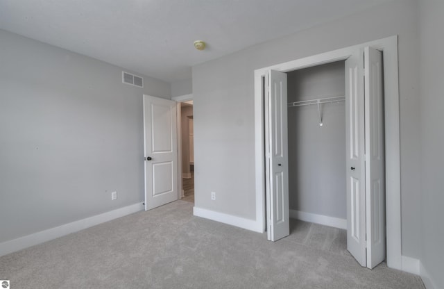 unfurnished bedroom with light colored carpet and a closet