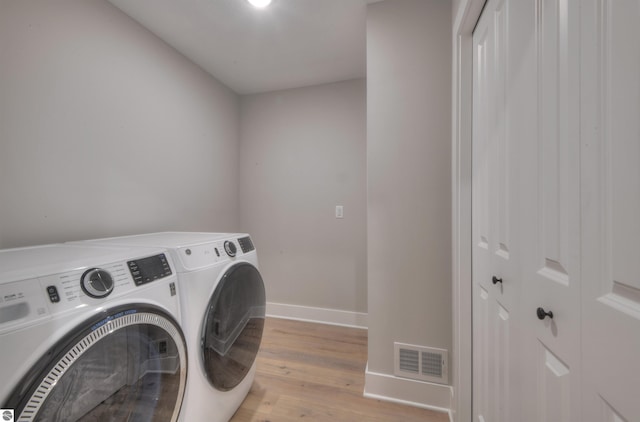 laundry area featuring separate washer and dryer and light hardwood / wood-style flooring