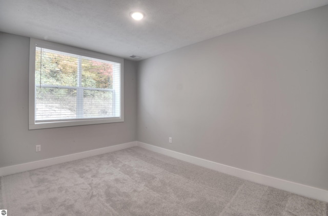 carpeted spare room with a textured ceiling and a wealth of natural light